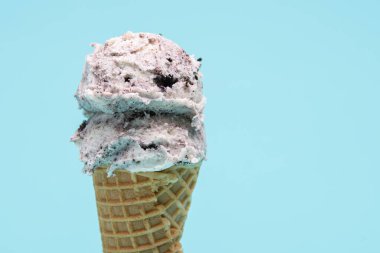 Lezzetli bir çift kepçe kurabiye ve dondurma, açık mavi bir arka fona kurulmuş gevrek bir waffle külahında oturur..