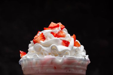 Çilekli milkshake, koyu arkaplanda berrak bardakta çikolata şurubu..