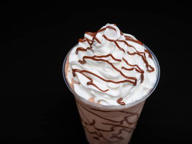 Çikolatalı milkshake, siyah arka planda berrak bir bardakta servis edilir. Ayrı bir içecek..
