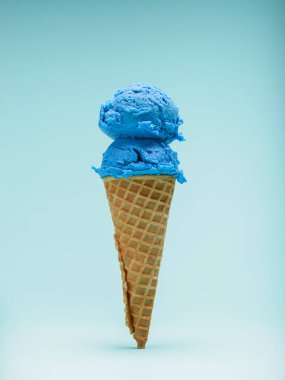 Mavi arka planda çift kepçe mavi sakızlı dondurma külahı..
