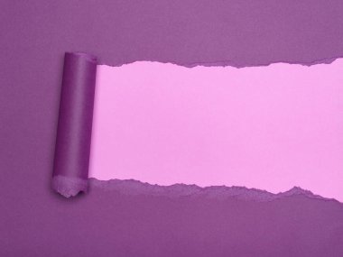 Mor bir kağıt parçası, altında daha açık pembe bir katmanı ortaya çıkarmak için yırtılır.