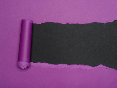 Yırtık mor bir kağıt parçası altında siyah bir arkaplan ortaya çıkarıyor..