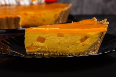 Çırpılmış kremayla süslenmiş lezzetli bir mango turtası, taze çilek ve çikolata aromalı. Koyu arkaplan.