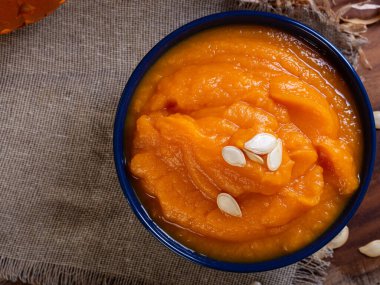 Bir kase canlı portakallı kabak püresi, balkabağı tohumlarıyla süslenmiş.