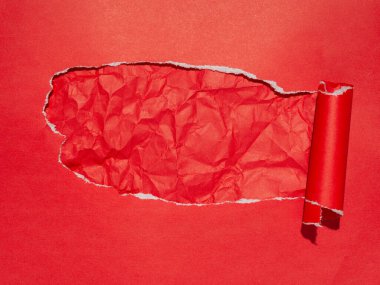 Kırmızı kağıt arka planda yırtık bir bölüm altında buruşuk bir dokuyu gösteriyor.