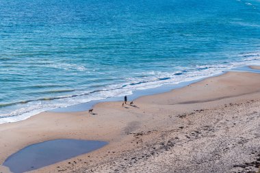 Maslin Sahili, ziyaretçileri altın kumlarına çeken nadir bir kış güneşi anı sunuyor. Yüksek kalite fotoğraf.
