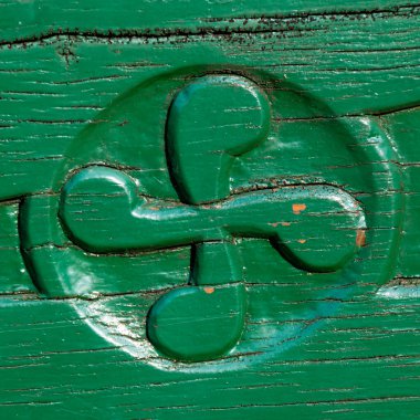 Old traditional Basque cross, also called lauburu, identity symbol of the Basque Country, carved in the wood of an exterior house beam and painted green