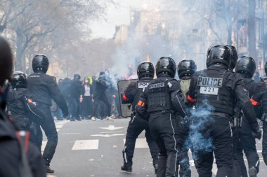 Paris, Fransa - 23 Mart 2023: Fransız çevik kuvvet polisi (Brav), Paris, Fransa 'da bir caddede düzenlenen emeklilik reformuna karşı düzenlenen bir protesto sonunda göz yaşartıcı gaz dumanı içinde isyancılarla karşı karşıya