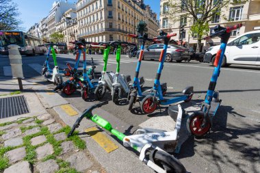 Paris, Fransa - 4 Nisan 2023: Paris, Fransa 'nın Şanzelize bölgesinde yol kenarına park etmiş çeşitli şirketlerden kiralık elektrikli scooterlar
