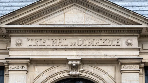 Close-up of a sign with the words 'Tribunal de Commerce' (meaning 'Commercial Court') written in French on the pediment of the commercial court building in Chartres, France