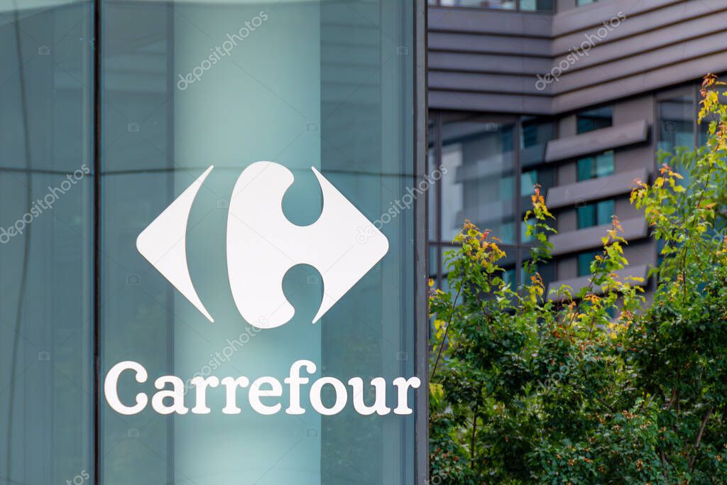 Massy, France - July 30, 2023: Sign and logo outside the building housing the world headquarters of Carrefour, a French multinational retail and wholesaling corporation with a global presence