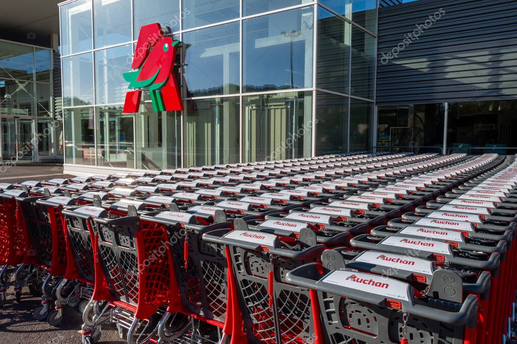 Gap, France - August 6, 2023: Rows of many branded shopping carts outside an Auchan supermarket. Auchan is a French company and a multinational retail group