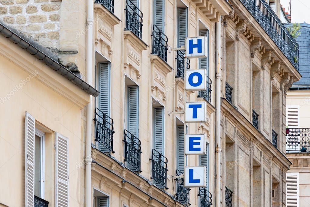 Sign with the word 'HOTEL' written in bright capital letters on the facade of a building in Paris, France