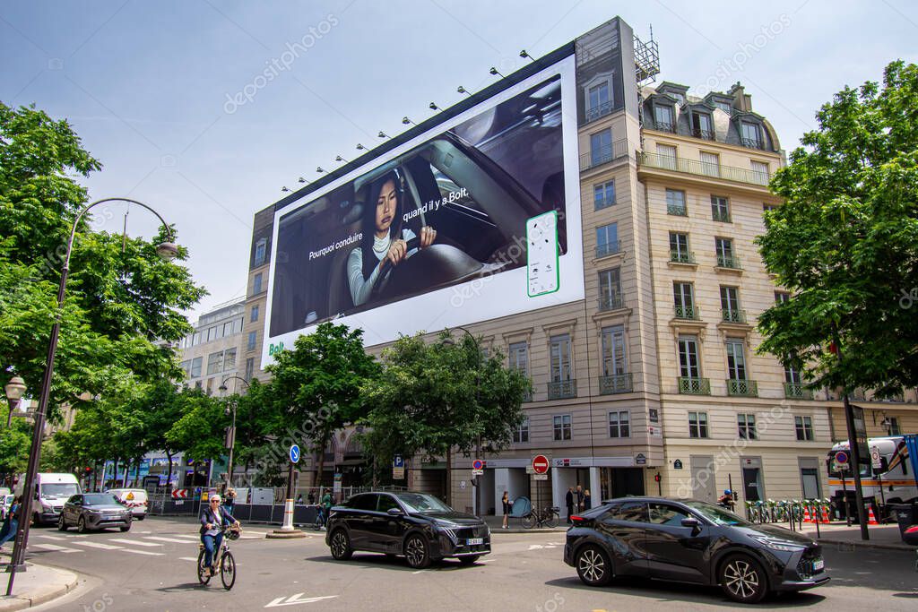 Paris, France - June 10, 2025: Large advertising billboard for Bolt, an Estonian app-based shared mobility company, covering the scaffoldings of the restoration works of a parisian building