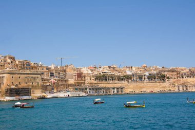 Valletta, Malta - 17 Haziran 2023: Valletta ve Vittoriosa arasında geçen botlar ve arka planda tipik luzzu ve Valletta