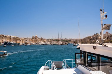 Vittoriosa, Malta - 17 Haziran 2023: Yatları ve tekneleri olan Vittoriosa limanı ve arka plandaki katedralin kubbesi feribottan alındı