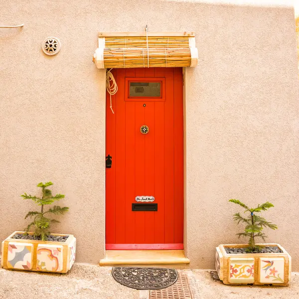 The Typical red door in Maltese villages with rolled up bamboo curtain cover