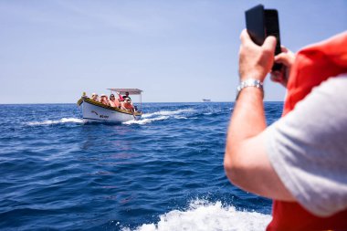 Zurrieq, Malta - 18 Haziran 2023: Turist dolu tekne Luzzu 'daki Blue Grotto, Malta' ya taşındı.