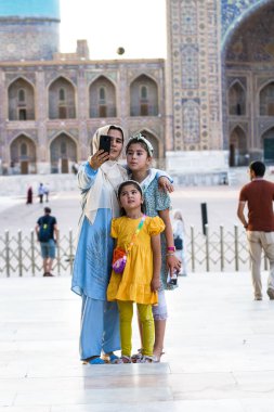 Semerkant, Özbekistan - 05 Temmuz 2024: Türbanlı Müslüman anne, Semerkant 'taki Registan Meydanı' nda kızlarıyla selfie çekiyor