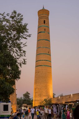 Khiva, Özbekistan - 10 Temmuz 2024: Özbekistan 'da Khiva sokaklarında gün batımında Juma Minaret turistlerle dolup taşıyor