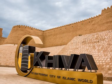 Khiva, Özbekistan - 11 Temmuz 2024: Özbekistan 'ın Khiva kentinin surları, önplanda Khiva' nın 2024 Turizm Kenti yazılı tabelaları.