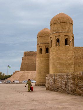 Khiva, Özbekistan - 11 Temmuz 2024: Özbek Kadın Çanta Taşırken Şehir Duvarları ve Gözetleme Kuleleri