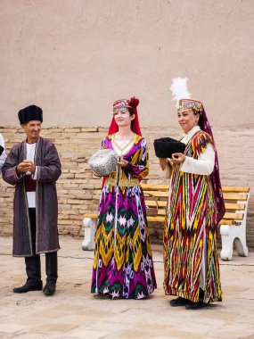 Khiva, Özbekistan - 11 Temmuz 2024: Geleneksel giysiler ve özgün ulusal başlık giyen bir grup Özbek, antik Khiva kentinde düzenlenen bir halk etkinliği sırasında üst üste poz verdi. Görüntü kültürel zenginliği ve çeşitliliği vurguluyor 