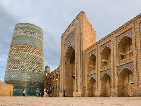 Khiva, Özbekistan - 11 Temmuz 2024: Orta Asya 'daki 19. yüzyıl İslami mimarisinin çarpıcı bir örneği olan Khiva' nın Itchan Kala kentindeki Muhammed Emin Han Madrasa 'nın tamamlanmamış Kalta Minor minaresi ve giriş portalı