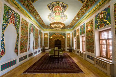 Khiva, Özbekistan - 12 Temmuz 2024: Özbekistan 'ın Khiva kentindeki Nurullabay Sarayı resepsiyon odasının içinde geleneksel bir toplantı masası ve tarihi dekorasyon seti bulunuyor..