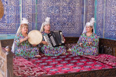 Khiva, Özbekistan - 13 Temmuz 2024: Özbekistan, Khiva 'da Han' ın hareminde oturan üç kadın müzik icra ediyor ve şarkı söylüyor