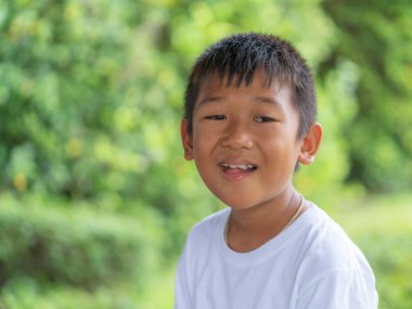 Bahçedeki bulanık yeşil arka planı olan Asyalı çocuğun portresi.