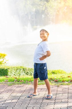 Şehir parkında sokakta duran sevimli çocuk, açık havayı seyretmeyi seviyor, su sıçratmayı ve işaret fişeği atmayı seviyor. Çocuklar için oyun ve eğlence alanları. Tatil ve tatil kavramı.