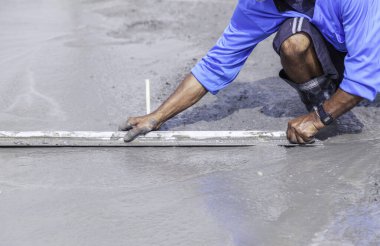Construction workers pouring concrete, Leveling concrete with trowels in construction area. Worker is holding  trowel to smooth leveling over freshly poured concrete.