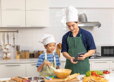 Babası dijital tarife bakıp evdeki mutfak odasında dokunmatik tablet kullanırken baba ve oğul yemek pişirir ya da hazırlarlar. Aile kaliteli boş vakitlerin keyfini çıkarıyor. Birlikte yemek hazırlıyoruz..