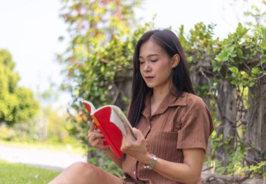 İlginç kitap mutluluğu okuyan çekici bir kadın. Güneşli bir günde fotokopi odasıyla birlikte şehir parkında oturuyor. Boş zaman kavramının tadını çıkarıyorum. Güneşli bir günde fotokopi çekilen şehir parkındaki minderde mutluluk. Boş zaman kavramının tadını çıkarıyorum..