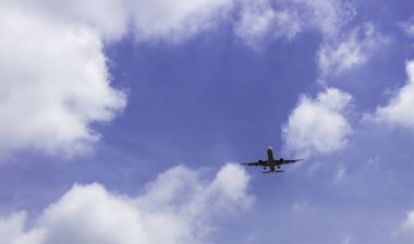 Mavi gökyüzünde ve beyaz bulutlarda uçan ticari havayolu şirketi. Uçağın uçuşu gözönüne alındığında. Yolcu uçağı mavi gökyüzünde uçuyor Güzel beyaz kabarık bulutlarla.