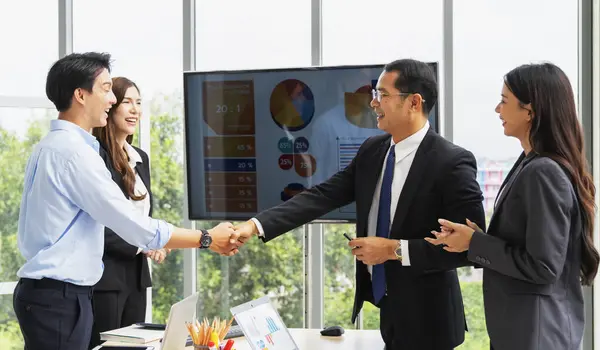Group of businessmen or entrepreneurs man and woman standing and holding hands happily after reaching business agreement.