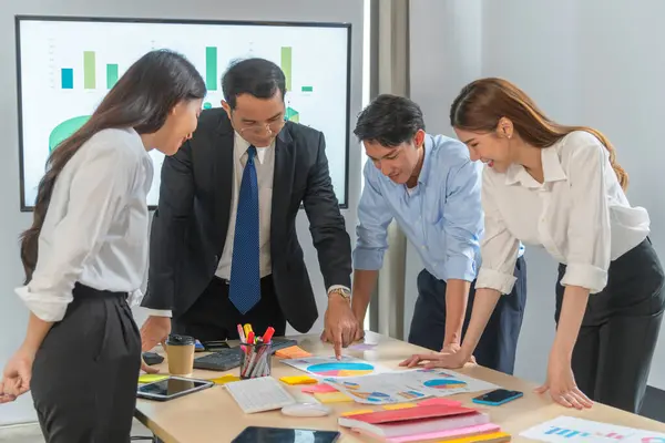 Middle-aged male investment manager is explaining pitfalls of investing on sheet of graph paper to new investor in order to achieve mistake-free investing.
