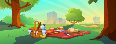 Şehir parkında çimenlikte piknik. Çağdaş yemek sepeti, taze meyve, iştah açıcı sandviç ve yerde bir şişe su, halk bahçesinde ağacın altında öğle yemeği, modern şehir manzarası.