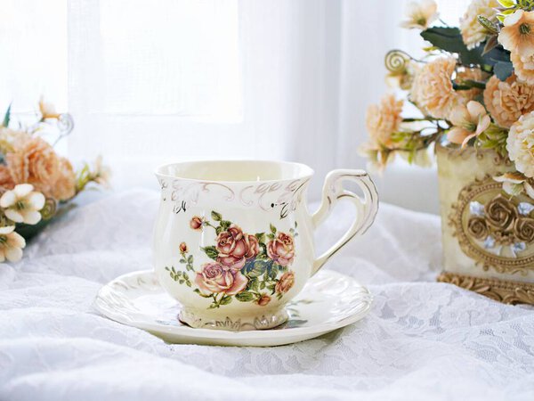 Antique cup of tea with yellow orange rose flowers background ,porcelain teacup vintage style ,old English coffee cup ,romantic roses backgrounds 