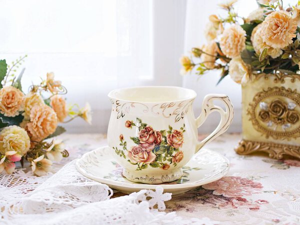 Antique cup of tea with yellow orange rose flowers background ,porcelain teacup vintage style ,old English coffee cup ,romantic roses backgrounds 