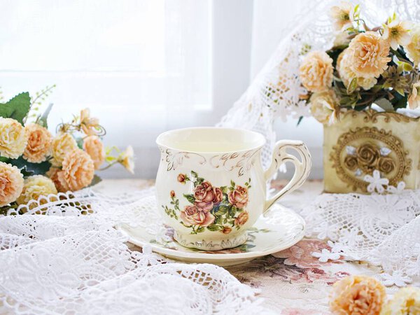Antique cup of tea with yellow orange rose flowers background ,porcelain teacup vintage style ,old English coffee cup ,romantic roses backgrounds 