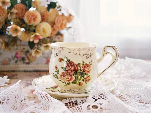 Antique cup of tea with yellow orange rose flowers background ,porcelain teacup vintage style ,old English coffee cup ,romantic roses backgrounds 