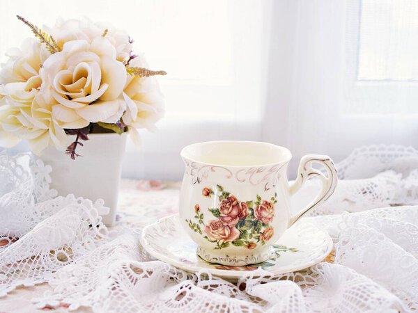 Antique cup of tea with yellow orange rose flowers background ,porcelain teacup vintage style ,old English coffee cup ,romantic roses backgrounds 