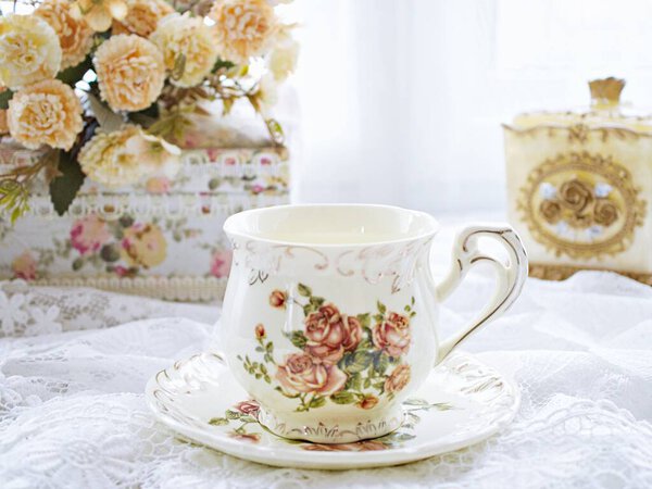Antique cup of tea with yellow orange rose flowers background ,porcelain teacup vintage style ,old English coffee cup ,romantic roses backgrounds 