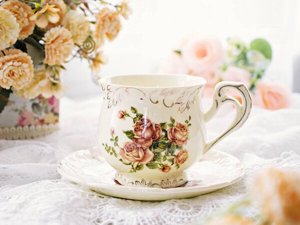 Antique cup of tea with yellow orange rose flowers background ,porcelain teacup vintage style ,old English coffee cup ,romantic roses backgrounds 