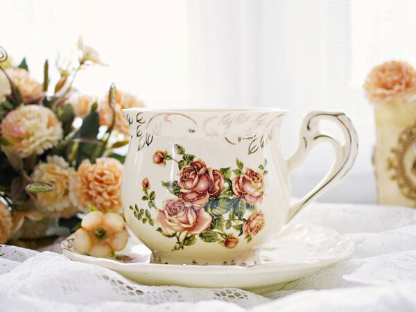 Antique cup of tea with yellow orange rose flowers background ,porcelain teacup vintage style ,old English coffee cup ,romantic roses backgrounds 