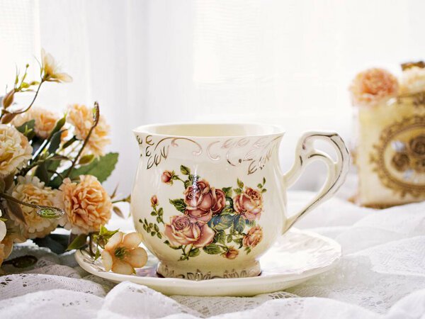 Antique cup of tea with yellow orange rose flowers background ,porcelain teacup vintage style ,old English coffee cup ,romantic roses backgrounds 