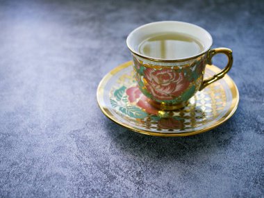 Koyu gri arka planda pembe gül porselen çay fincanı ile romantik çay saati afişi, boşluğu kopyala
