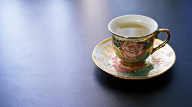 Koyu gri arka planda pembe gül porselen çay fincanı ile romantik çay saati afişi, boşluğu kopyala